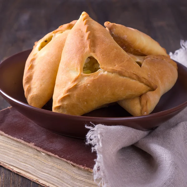 Pasteles caseros con papas y cebollas en un tazón de cerámica en un libro de cocina antiguo —  Fotos de Stock