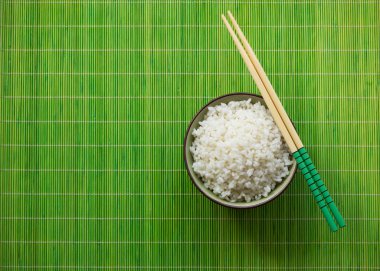 Yeşil bir saman mat yemek çubukları ile haşlanmış pirinç