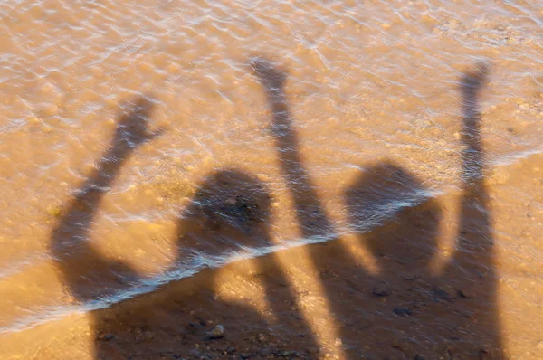 The shadow men and women on the sand, waving their hands in the air