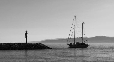 Limandan ayrılan bir yelkenlinin romantik siyah beyaz fotoğrafı.,