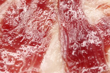 Elle kesilmiş İber jambonu dilimlerinin makrofotografı, doğal yağ damarların arasına sızar, iyileşmiş etleri hamile bırakır.,