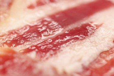 Elle kesilmiş İber jambonu dilimlerinin makrofotografı, doğal yağ damarların arasına sızar, iyileşmiş etleri hamile bırakır.,