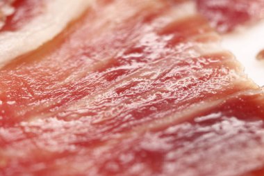 Elle kesilmiş İber jambonu dilimlerinin makrofotografı, doğal yağ damarların arasına sızar, iyileşmiş etleri hamile bırakır.,