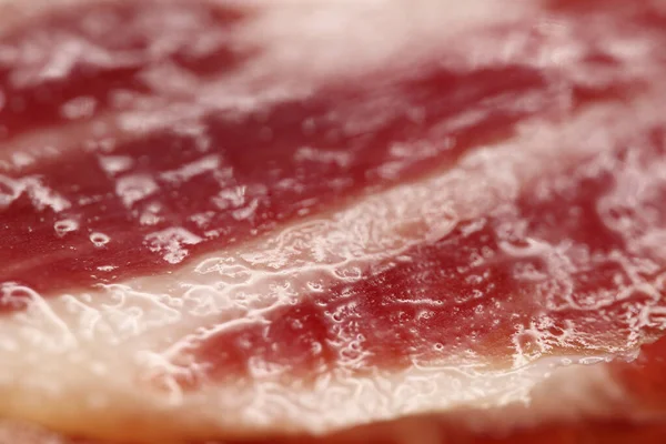 Elle kesilmiş İber jambonu dilimlerinin makrofotografı, doğal yağ damarların arasına sızar, iyileşmiş etleri hamile bırakır.,