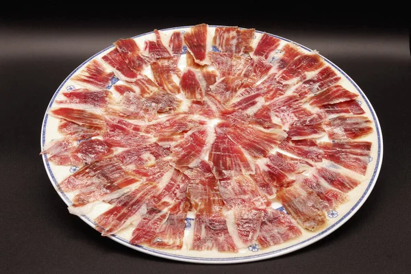 Siyah arka planda İber jambonu dolu yuvarlak bir hayat,