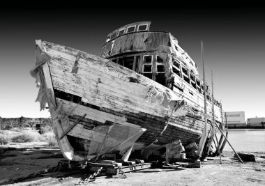 İnsanları ve turistleri deniz kıyısına taşımak için eski bir çürüyen teknenin siyah beyaz fotoğrafı.,