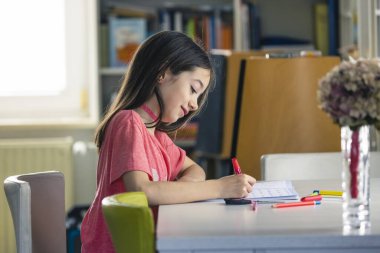 Küresel virüs salgını yüzünden evde eğitim. Karantina sırasında evde ödevini yapan genç bir kız.. 