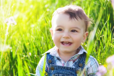 Mutlu küçük çocuk gülerek ve yaz yeşil çim gülümseyen.