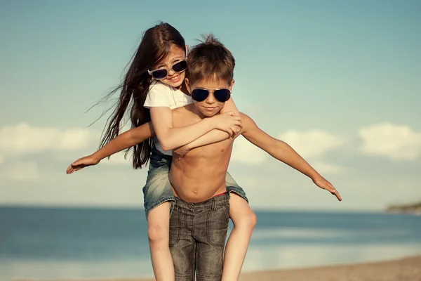 Szczęśliwe dzieci w okulary, zabawy nad morzem. Chłopiec i dziewczynka — Zdjęcie stockowe