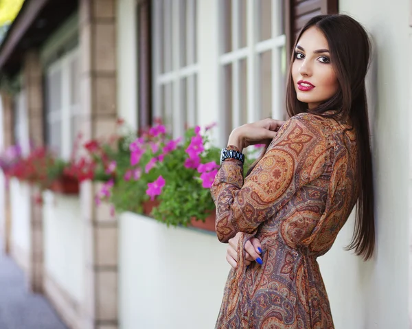 Mooie elegante vrouw in romantische jurk over de muur met flo — Stockfoto