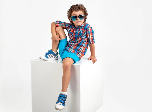 Lindo y divertido niño en camisa a cuadros y pantalones cortos azules —  Fotos de Stock