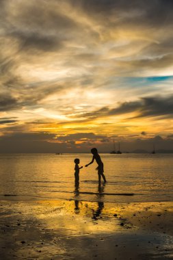 Two kids plaing on the beach at amazing beautifull sunset clipart