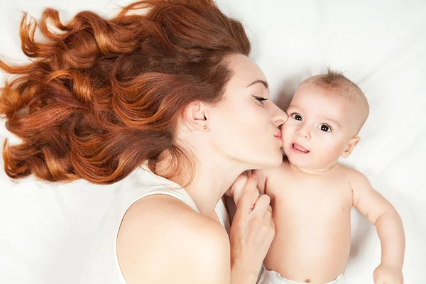 Glad familj koncept. Vacker ung röda haired mamma kysser — Stockfoto