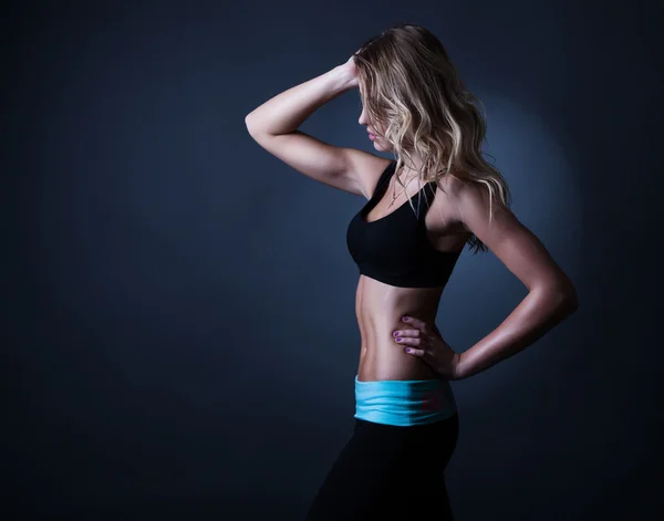 Sport blond kvinna med vågigt hår visar henne väl tränad kropp en — Stockfoto