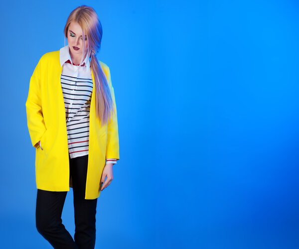 Fashion portrain of blond woman in trendy yellow jacket over blu