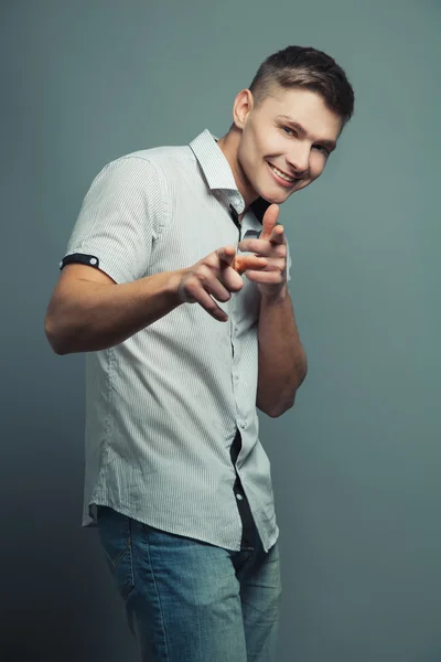 Homem bonito em t-shirt e jeans sorrindo e olhando para a câmera — Fotografia de Stock