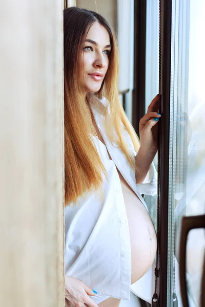 Mulher grávida bonita perto da janela . — Fotografia de Stock