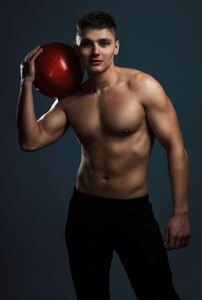 Handsome athletic man with red ball showing his muscular body. — Stock Photo, Image