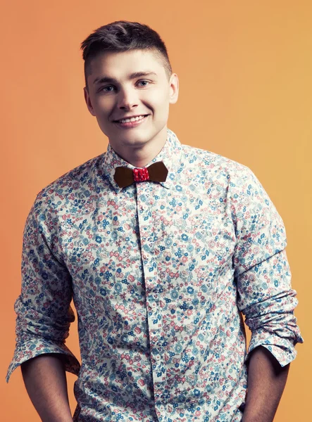 Homem bonito na camisa da moda e bowtie sorrindo sobre ba laranja — Fotografia de Stock