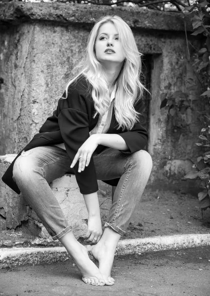 Sexy blond woman in trendy jeans and black jacket sitting barefo — Stock Photo, Image