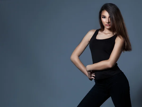 Fashion woman standing over grey background in black clothes. — Stock Photo, Image