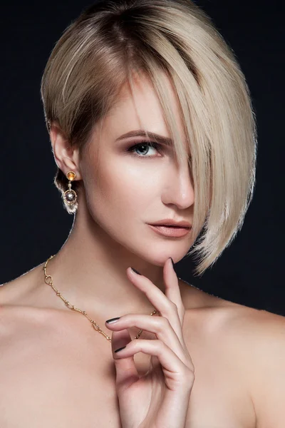 Schöne junge Frau mit elegantem stylischem Haarschnitt und Ohrringen — Stockfoto