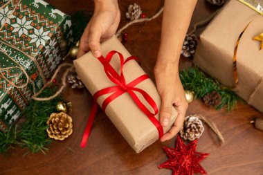 Noel hediyesi tutan bir kadının elleri. Hediyenin kırmızı bir kurdelesi ve yıldızı var.