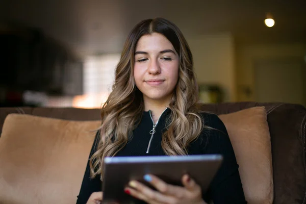 Koltuğunda oturan genç bir kadın tabletine bakıyor.