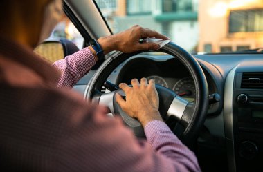 Adam arabasının direksiyonunu havluyla temizliyor.