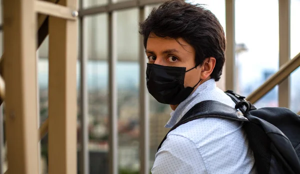 Maskeli bir gencin portresi, yemek merdivenlerinde oturuyor.