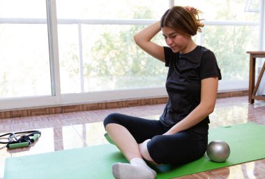 Genç ve formda bir kadın evde spor yapıyor.