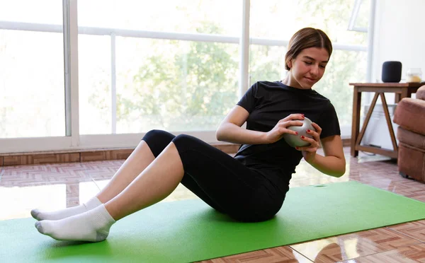 Genç ve formda bir kadın evde spor yapıyor.