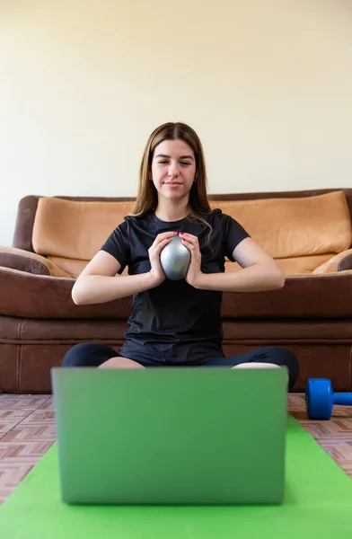 Spor giyim sektöründe kararlı bir bayan sporcu dizüstü bilgisayarda video dersi izliyor ve evde egzersiz yapıyor.