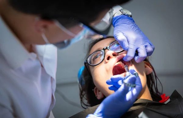 Series of photos at a dentist\'s office. A young brunette woman sitting in a dentist\'s chair. A dentist giving her a lip injection