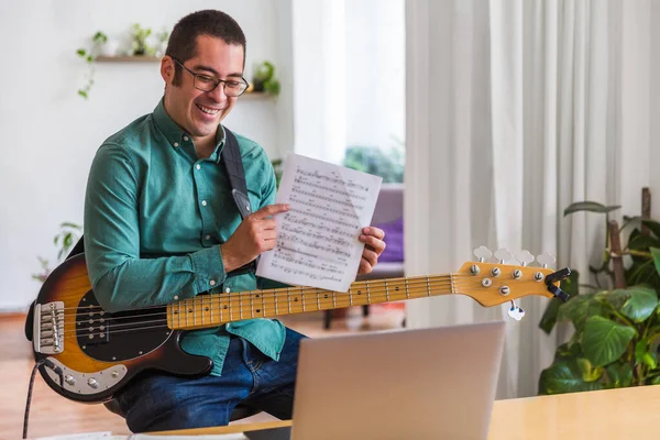 Genç adam dizüstü bilgisayarla masada oturuyor. Canlı müzik öğretiyor.
