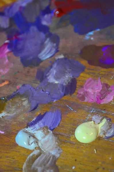 Karışık ve karıştırılmamış akrilik renklere sahip bir ressam paletinin stok fotoğrafı