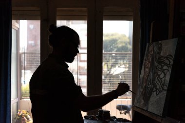 Genç bir erkek ressamın silüetinin doğal ışıkla iç içe soluk soluğa fotoğrafı.