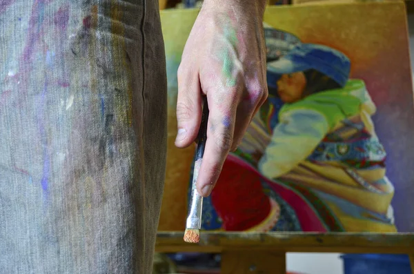 Stock photo of a male artist hand with brush and colours on skin. Paint stains