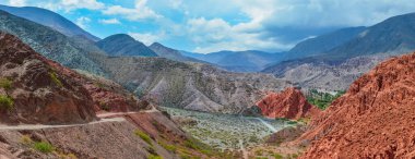 Arjantin, Jujuy 'daki Purmamarca köyündeki renkli tepelerin ve dağların panoramik fotoğrafı. Peyzaj