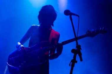 Tanınmayan kadın kısa saç gitaristi. Müzik ışıkları rock grubu konserinde silueti gösteriyor. Sisli ışık