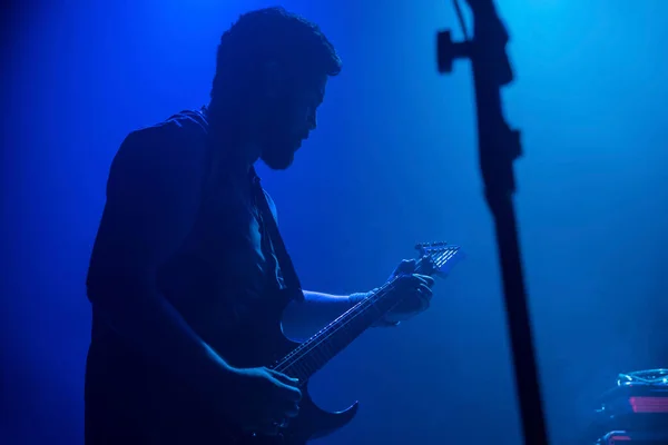 ロックバンドライブでエレキギターを弾くミュージシャン 黒髪男性ギター奏者がステージ上で演奏 音楽霧灯ショーシルエット — ストック写真