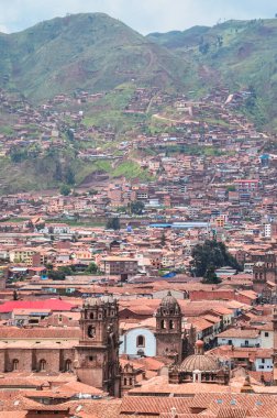 Yeşil tarlalarla çevrili Cusco şehrinin çatılarının havadan görüntüsü. Uzak bir noktadan evler ve kiliseler. Peru, Güney Amerika