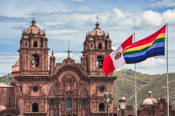 Peru 'nun Cusco Katedrali manzaralı ve rüzgarla dalgalanan ve dalgalanan bayraklı. Fotoğraf, Cusco 'nun ana şehir meydanından. Altında yeşil tepeler ve gökyüzü var. Peru, Güney Amerika