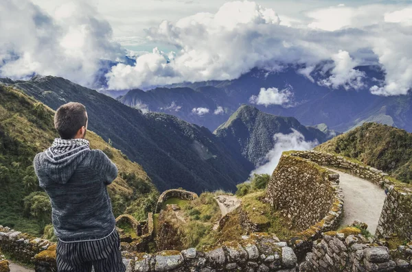 Phuyupatamarca harabelerinde, önünde uzanan büyük vadiyi düşünen bir adamın yüksek açılı arka görüntüsü. Peru 'daki Machu Picchu arkeolojik alanına giden İnka yolu. Güney Amerika