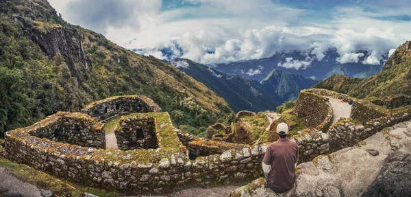 Phuyupatamarca harabelerinde önündeki büyük vadiyi düşünen bir adamın yüksek açılı panoramik görüntüsü. Peru 'daki Machu Picchu arkeolojik alanına giden İnka yolu. Güney Amerika