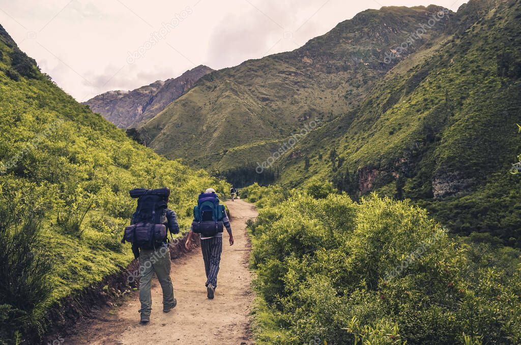 Male backpackers surrounded by hills and mountains hiking the inca trail to Machu Picchu archaeological site from the Inca's ancient civilization in Peru. South America