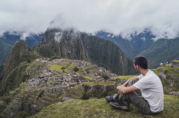 Oturan genç adam, Machu Picchu 'yu düşünerek Huayna Picchu dağıyla birlikte şehri kaybetti. Cusco Eyaleti 'nin kutsal vadisindeki antik inka medeniyetinin kalıntıları. Peru, Güney Amerika