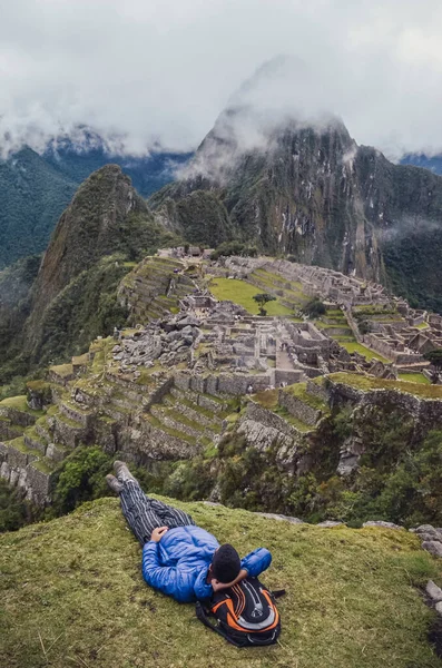 Genç adam uzanmış, Machu Picchu 'nun Huayna Picchu dağıyla kayıp şehrini düşünüyor. Cusco Eyaleti 'nin kutsal vadisindeki antik inka medeniyetinin kalıntıları. Peru, Güney Amerika