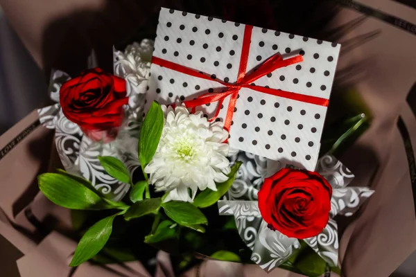 3 red roses  bouquet with gift envelope, red ribbons, white paper for certificates, invitation card inside. Craft concept. Red on the red background.   Weddig, ceremony concept, holidays, surprises.