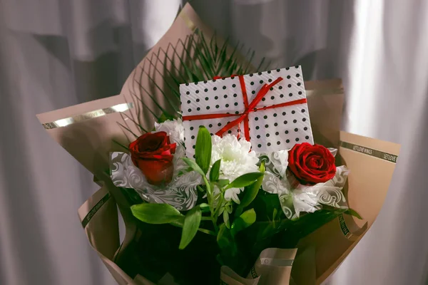 3 red roses  bouquet with gift envelope, red ribbons, white paper for certificates, invitation card inside. Craft concept. Red on the red background.   Weddig, ceremony concept, holidays, surprises.